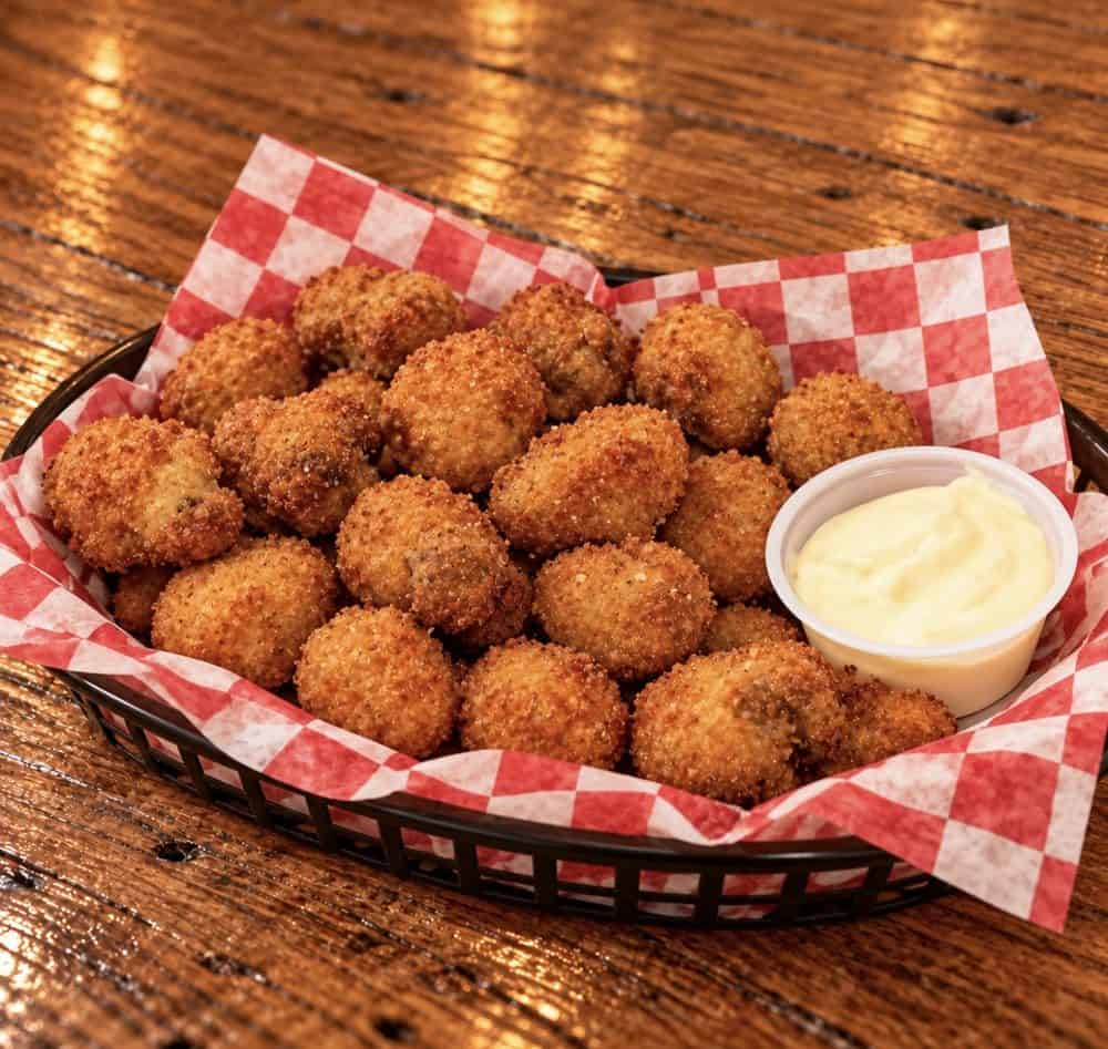 lipw-breaded-mushrooms-web Golden breaded mushrooms in a basket lined with red-and-white checkered paper, served with dipping sauce.