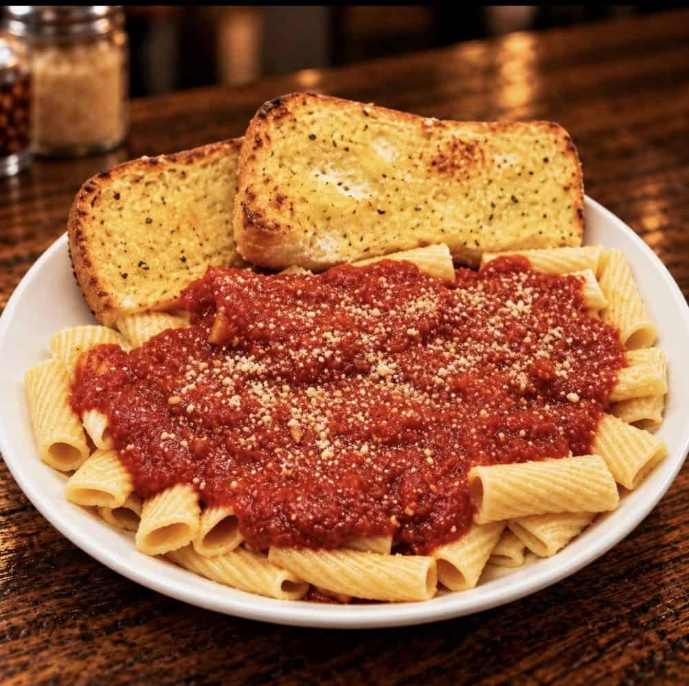 Rigatoni topped with tomato sauce and grated cheese, served with two slices of toasted garlic bread.