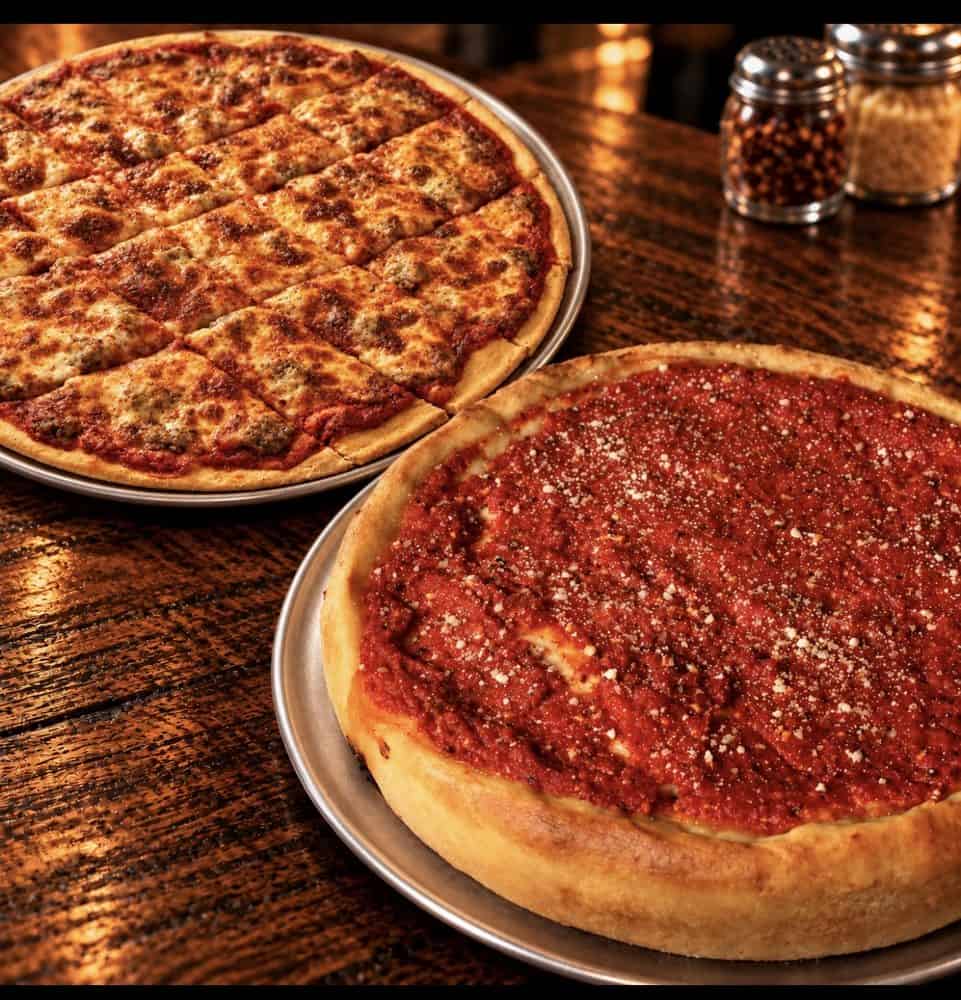 Square-cut thin-crust sausage pizza beside a Chicago-style stuffed pizza topped with tomato sauce and grated cheese.